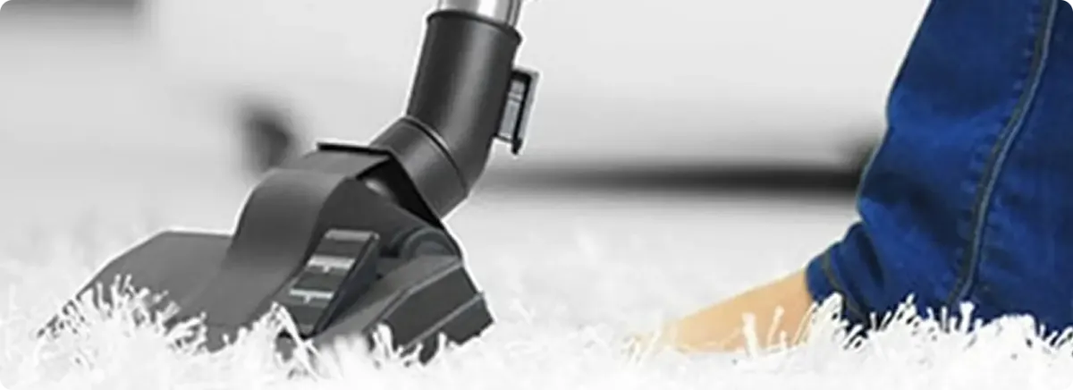 Close-up of a professional vacuuming a white carpet in Boynton Beach.